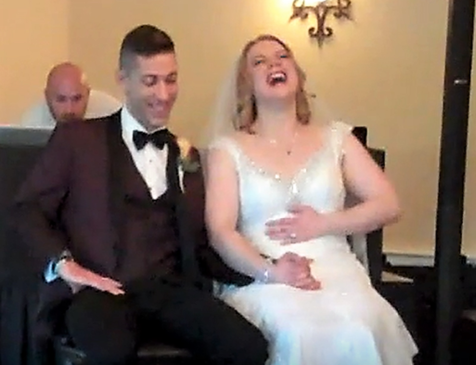 A bride and groom laughing as their love story plays for their guests
