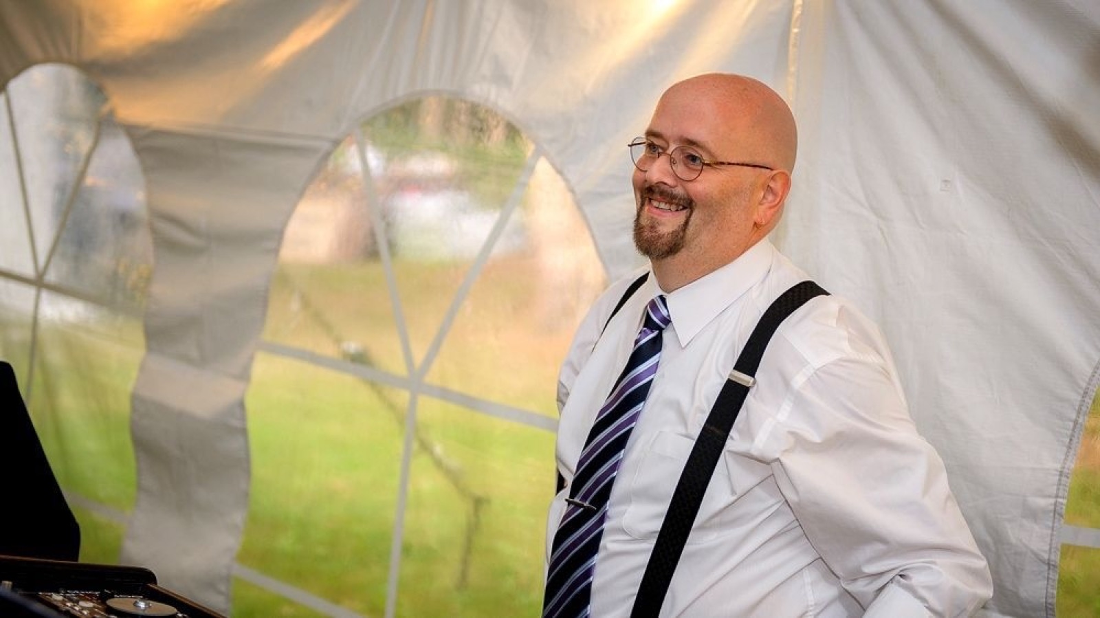 Zac smiling at a wedding reception in a tent